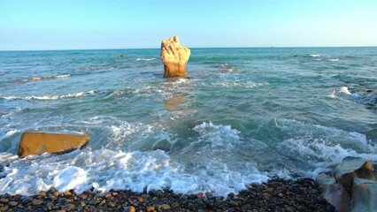 Wall Mural - Waves crashing on the shore creating silk like streaks of different shapes piercing the rock at the beach in the afternoon is beautiful and relaxing