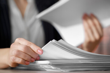 Woman reading documents at table in office, closeup. Space for text