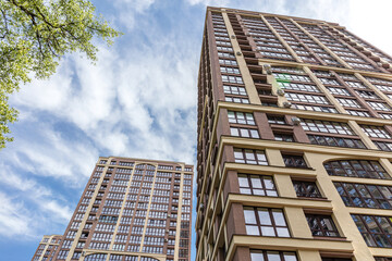 Wall Mural - modern apartment buildings against bright blue cloudy sky. low angle view.