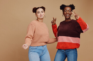 Peace sign, fashion and women friends in studio with hand gesture, smile and happiness on brown background. Love, friendship and black woman with happy girl for relaxing, cosmetics and emoji together