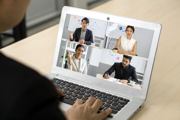 Back view of businessman sit at desk in office typing on laptop computer keyboard while  videoconference on-line meeting with business partner.