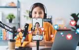 Fototapeta  - Vlogger live streaming podcast review on social media, Young Asian woman use microphones wear headphones with laptop record video. Content creator concept.