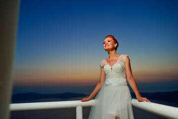 Wall Mural - Pretty woman posing in white wedding dress on Santorini island, Greece