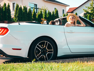 Portrait of two young beautiful and smiling hipster female in convertible car. Sexy carefree women driving cabriolet. Positive models riding and having fun in sunglasses outdoors. Enjoying summer days