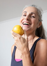 Happy Mature Woman Eating Apple At Home