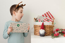 Cute Boy Looking At Advent Gifts In Basket By Wall