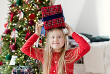 Surprised Girl Holding Christmas Gift On Head At Home