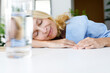 © Westend61 - Smiling woman taking nap by glass of water on desk