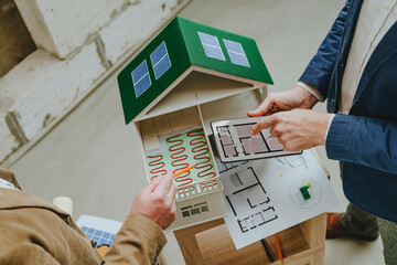 Architect explaining colleague underfloor heating of house using tablet PC at construction site