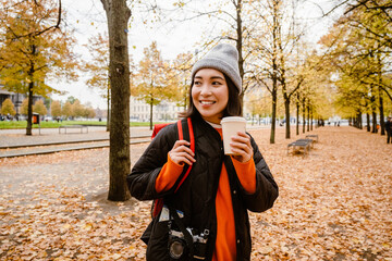 Wall Mural - Beautiful smiling asian woman drinking takeaway coffee during walk in park