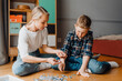 © Drobot Dean - Mom and son playing with puzzle pieces while sitting on floor