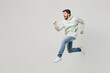 © ViDi Studio - Full body side view overjoyed cheerful happy excited young caucasian man wear mint hoody jump high run fast hurry up isolated on plain solid white background studio portrait. People lifestyle concept.