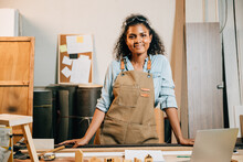 Portrait Of Africa American Beautiful Young Black Woman Carpenter Wearing Protective Goggles On Head Standing On Workspace Table At Workshop Against Wood Or Woodshop, National Carpenters Day