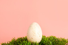 White Spotted Easter Egg On Green Grass On Pink Background