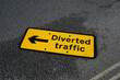 diverted traffic sign with arrow laying flat on road surface. amber warning sign to divert vehicles from road works site. 