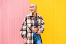 Happy Woman With Shaved Head Wearing Plaid Jacket Standing In Front Of Wall
