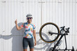 © VISTA by Westend61 - Happy cyclist showing thumbs up gesture standing in front of wall