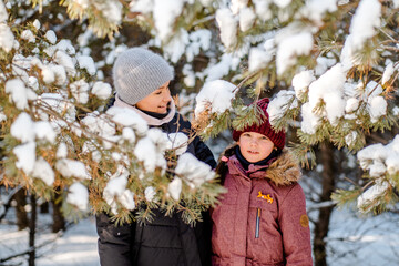 Family winter walk in the forest. Raising a child, family habits. Mother and daughter are having fun in winter in the forest in sunny frosty weather. A mother's hug.