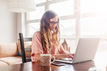 Poster - Happy young woman working with laptop at home