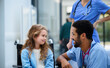 © Halfpoint - Young multiracial doctor talking with little girl on wheelchair.