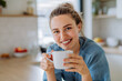 © Halfpoint - Young woman enjoying cup of coffee at morning, in her kitchen.