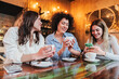 © Jose Calsina - Group of three young females smiling and taking a coffee in a restaurant. Multiethnic women friends talking and having fun in a bar holding a cup. High quality photo