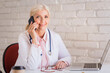 © gzorgz - Smiling female doctor having a call while sitting at doctor's office