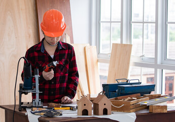 Wall Mural - Lovely Asian carpenter boy acting present his work in front of DIY woodworking table carpentry shop with copy space