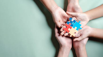 Color puzzle symbol of awareness for autism spectrum disorder family support. Father, Mother, Children holding jigsaw puzzle Autism World Awareness Day.