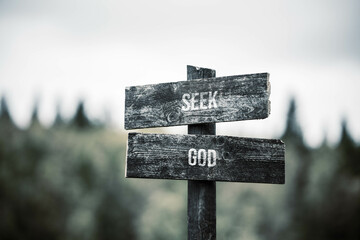 vintage and rustic wooden signpost with the weathered text quote seek god, outdoors in nature. blurred out forest fall colors in the background.