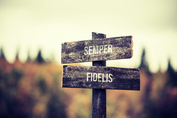 vintage and rustic wooden signpost with the weathered text quote semper fidelis, outdoors in nature. blurred out forest fall colors in the background.