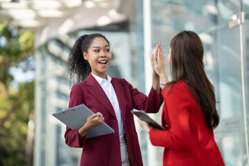 Aufkleber - Two Asian businesswomen discussing business information while standing outside the office.