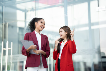 Aufkleber - Two Asian businesswomen discussing business information while standing outside the office.