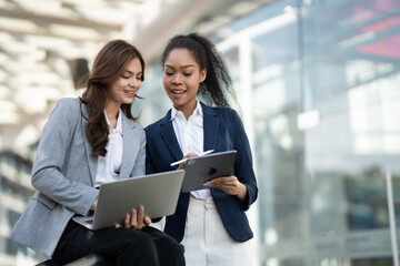 Aufkleber - Two Asian businesswomen discussing business information while standing outside the office.