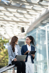 Aufkleber - Two Asian businesswomen discussing business information while standing outside the office.