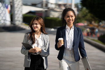 Aufkleber - Two Asian businesswomen discussing business information while standing outside the office.