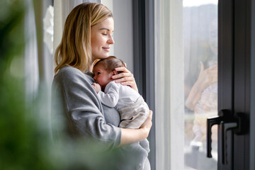 Loving mother hugs her little baby at home