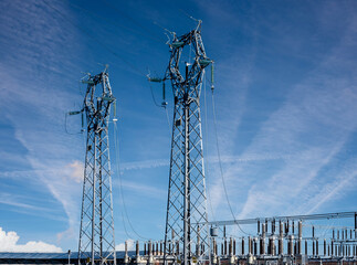 Electric high voltage pylons on Power station electric distribution center over blue sky with streaky clouds, copy space