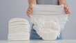 A woman chooses an adult diaper from a pile. Urinary incontinence problem.