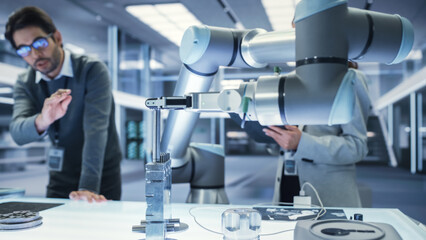 Aufkleber - Close Up Shot of a Modern Robotic Arm Holding and Moving a Mechanical Metal Component. Diverse Team of Engineers Using Tablet Computer to Manipulate and Program the Robot.