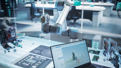 Fototapete - Over the Shoulder Shot of a Robotics Engineer Using a Laptop Computer with a Software Operating the Robotic Arm. Robot Hand Holding a Microchip. Automation Startup Research and Development Office.
