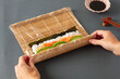 © ADDICTIVE STOCK - Crop person rolling sushi with bamboo mat