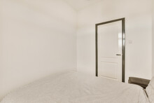 A Bedroom With White Walls And Black Trim Around The Bed, There Is A Door That Leads To Another Room