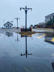 Large puddles of water with reflection on light pole after water went over the docks in Babylon
