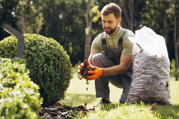 Gardner holding package of tree bark to cover the ground