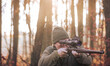 © Khaligo - Autumn hunting season, hunter with rifle looking out for some wild animal in a wood or forest, outdoor sports concept