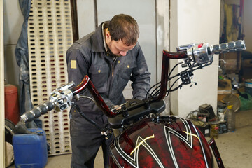 Poster - The mechanic connects the electrical cables of the motorcycle.