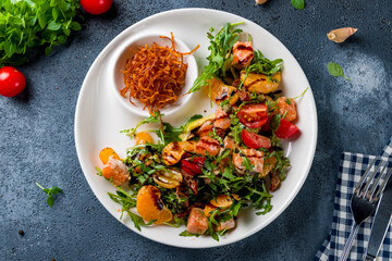 mixed salad with salmon and orange top view on white plate