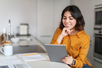 Modern Technologies. Young Smiling Arab Woman Using Digital Tablet In Kitchen