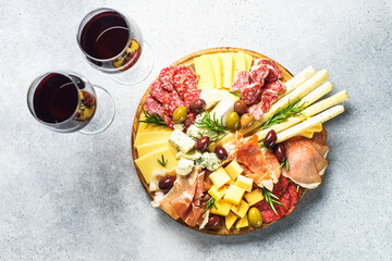 Sticker - Antipasto at wooden serving board with wine. Cheese and meat - jamon, salami with olives. Top view at stone table.